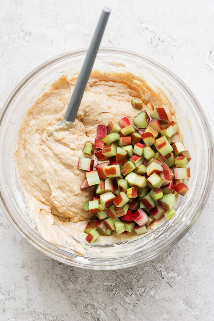 muffin batter and chopped rhubarb in a clear mixing bowl