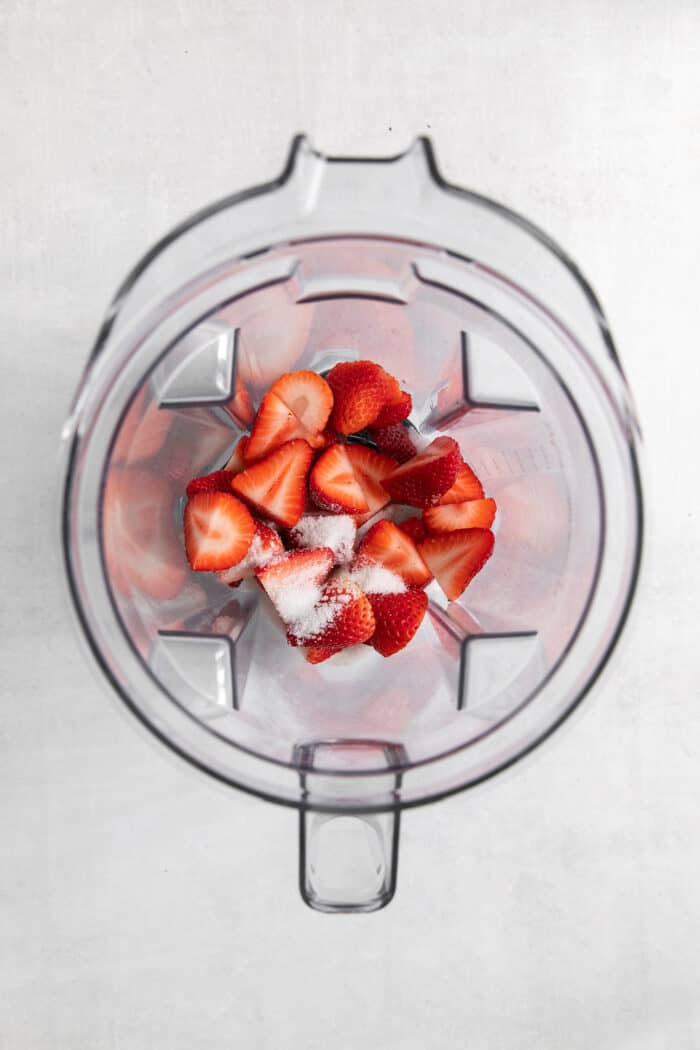 Strawberries and sugar are added to a blender for puree.