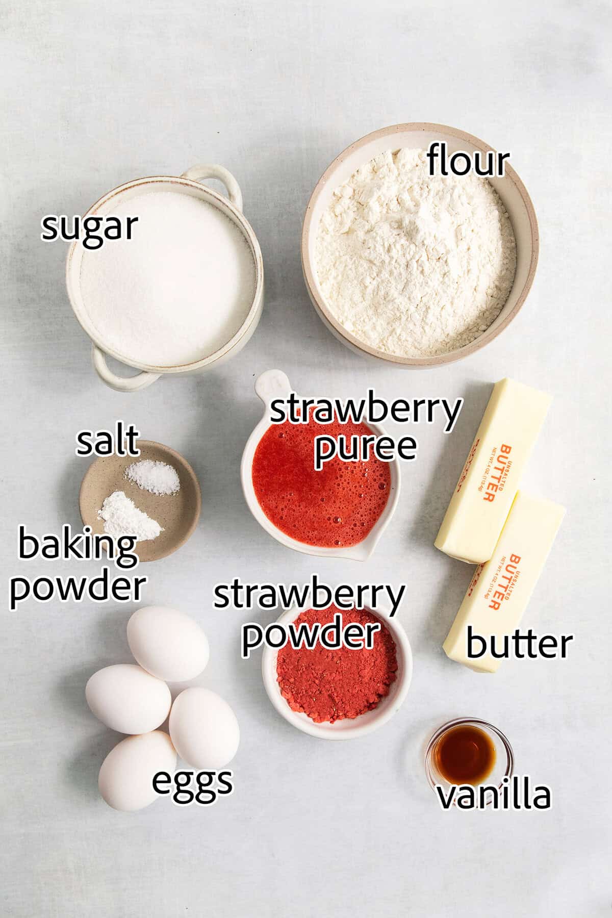 Ingredients for strawberry brownies are shown labeled and portioned: strawberry powder, strawberry puree, baking powder, sugar, flour, butter, vanilla, eggs.