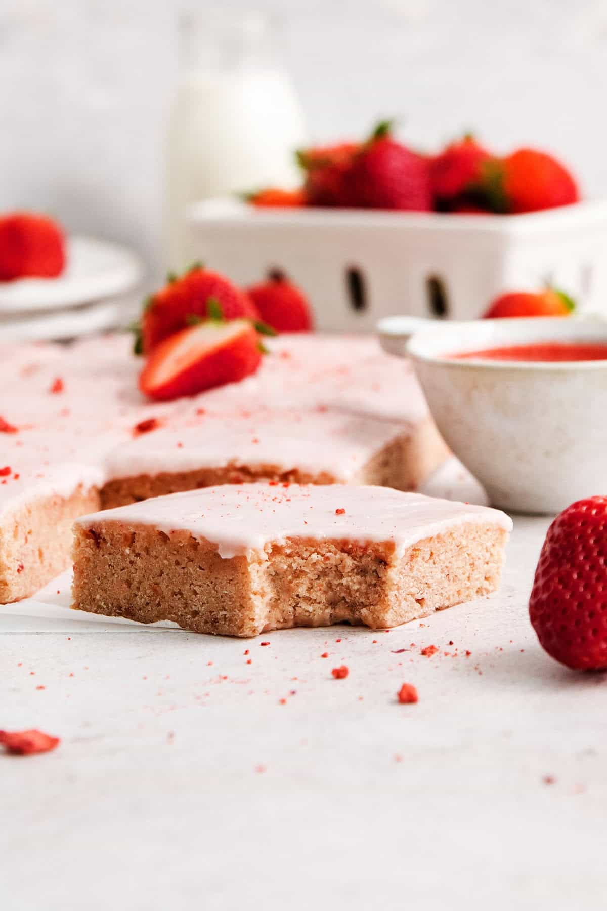 A pink strawberry bar on a white surface with a bite taken out.