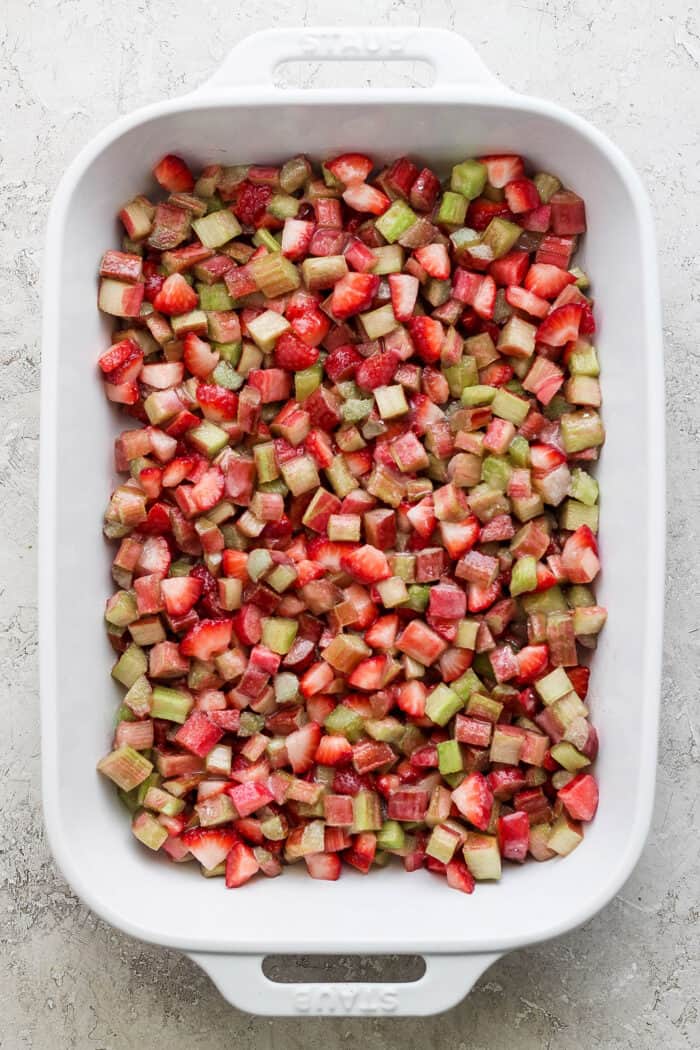 chopped strawberry and rhubarb filling in a white rectangular baking dish