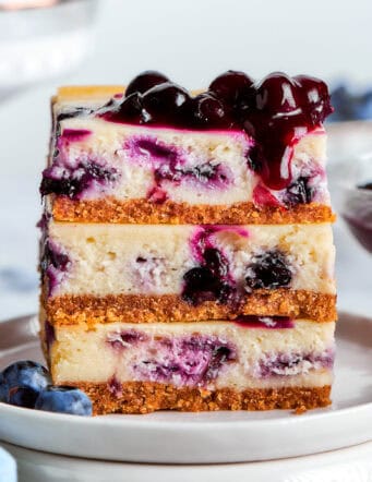a stack of 3 blueberry cheesecake bars on a white plate