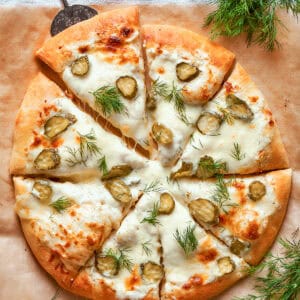 overhead photo of a whole pickle pizza cut into individual pieces