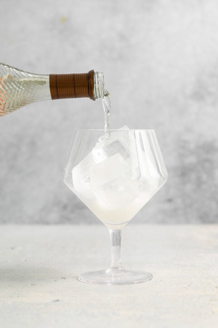 Prosecco is added to a glass with ice.
