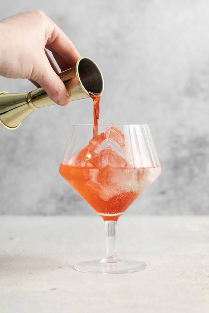 Campari is poured into the glass.