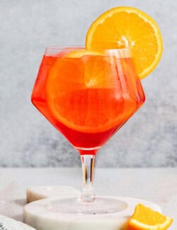 a glass of Campari spritz with an orange wheel garnish