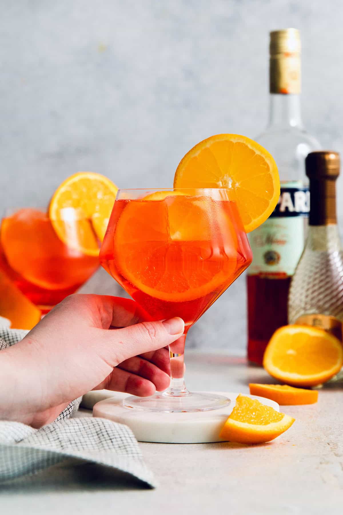 a hand holding a Campari spritz cocktail