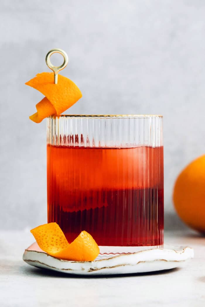 A beautiful red Negroni in a cocktail glass with orange peels.