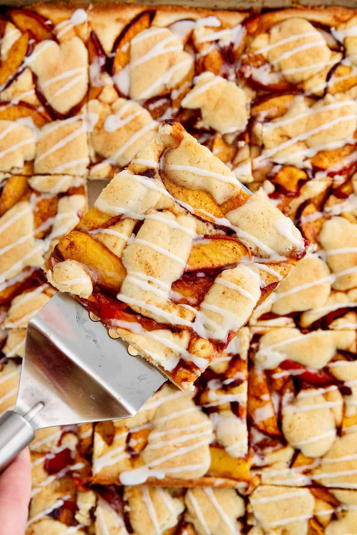 A serving spatula lifts out a peach bar.
