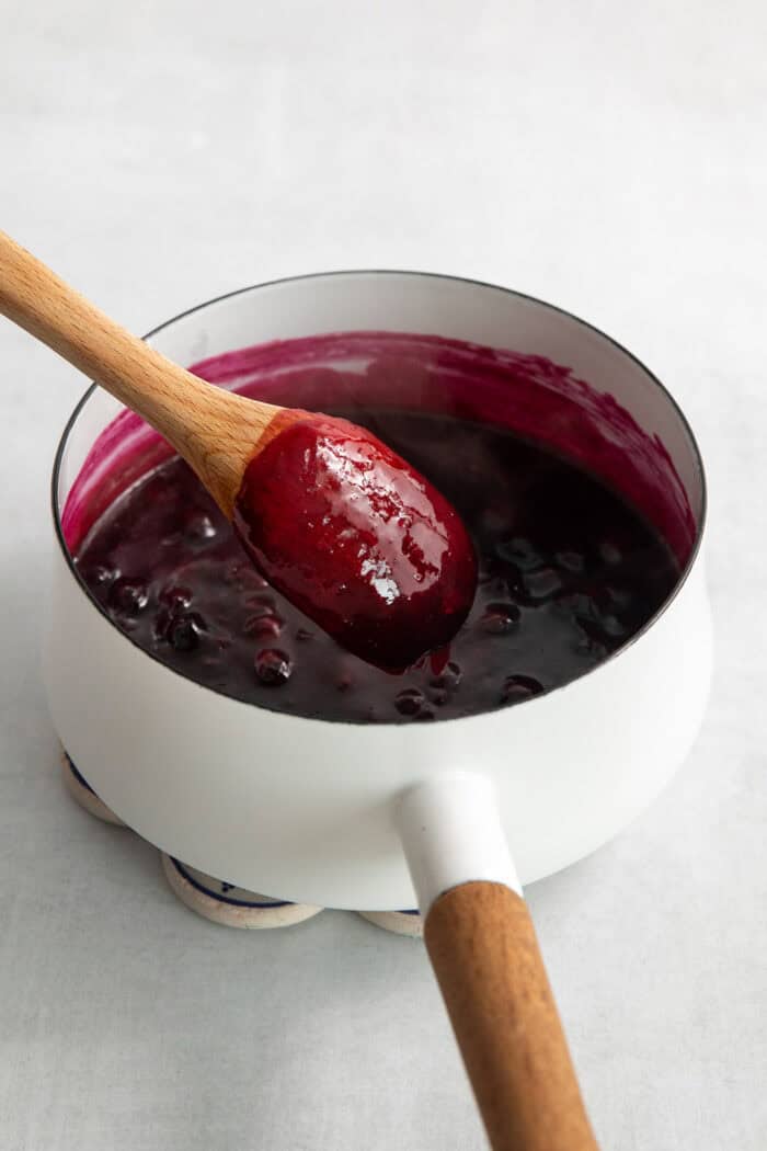 Blueberry sauce is mixed in a pot.