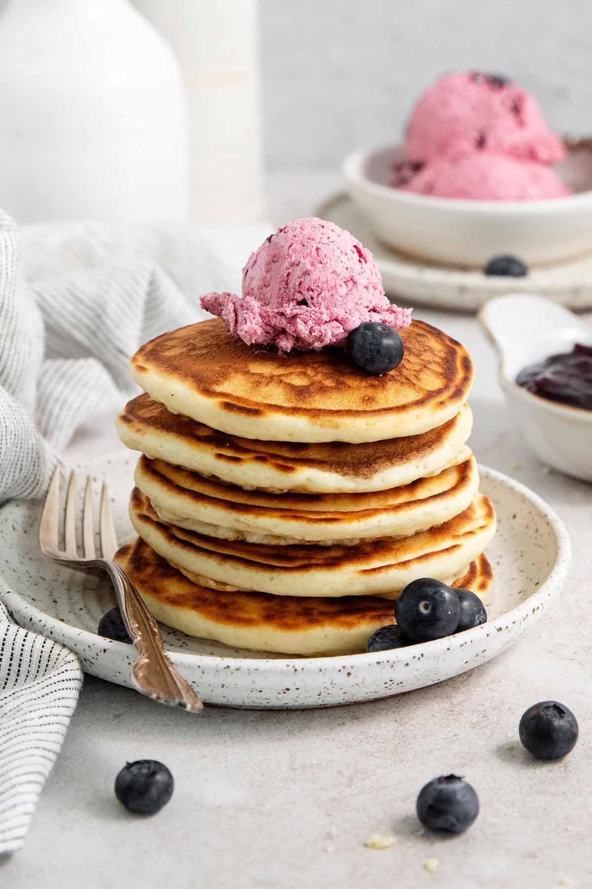 A stack of pancakes on a plate is topped with blueberry butter.