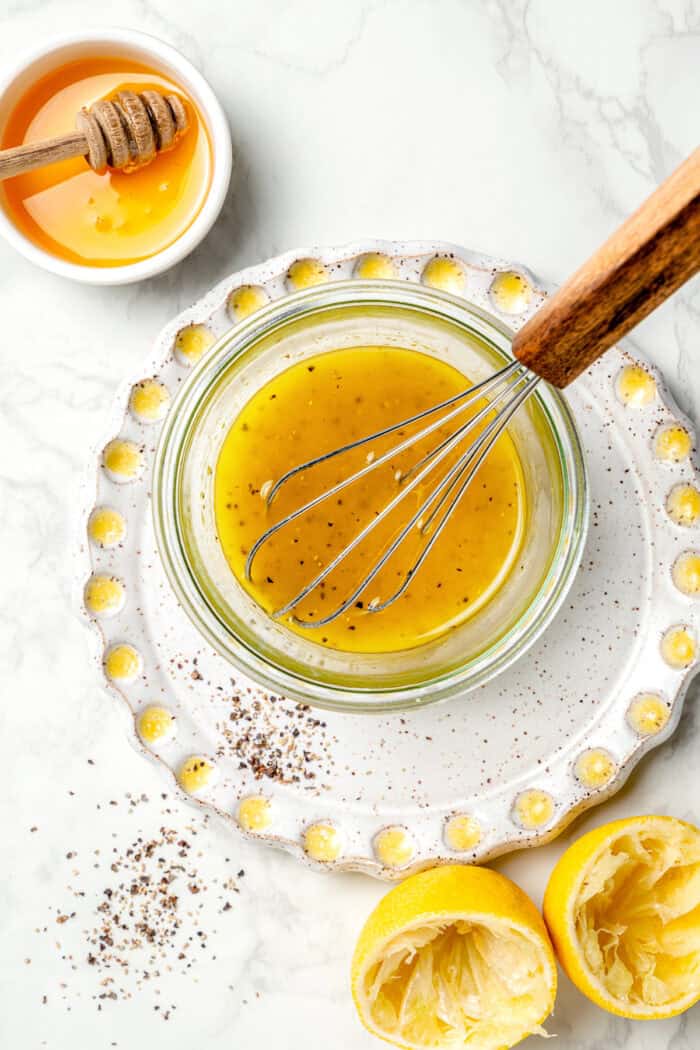 The dressing for grilled peach salad is whisked in a bowl.