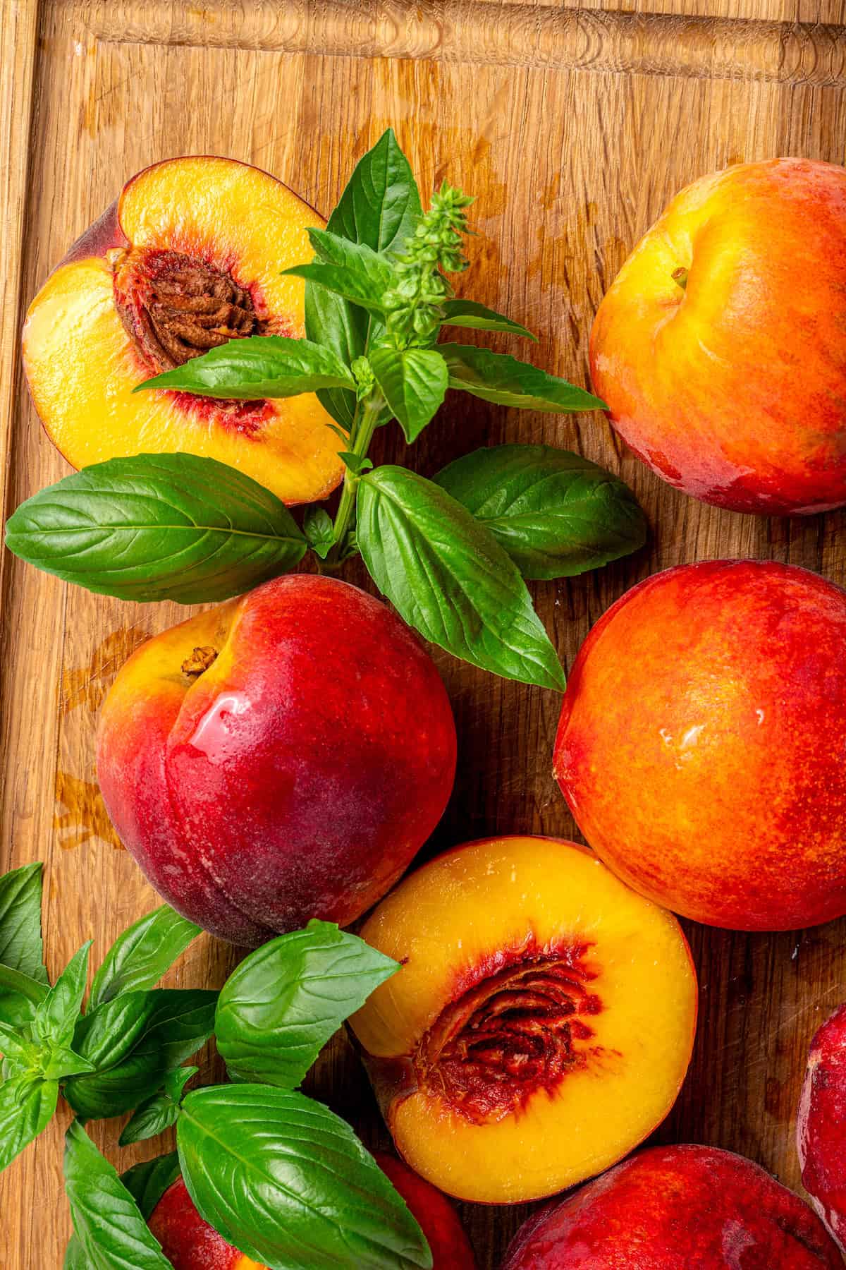 Peach halves are topped with fresh basil leaves.