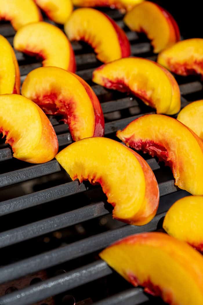 Peach slices are placed on a grill.