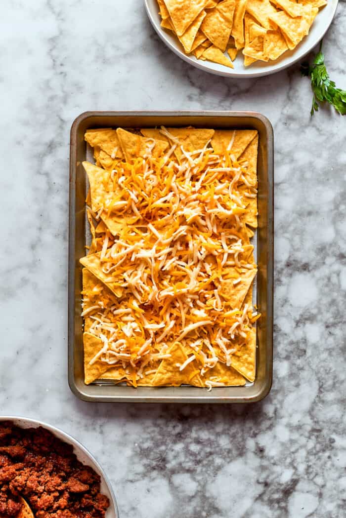 Cheese is added to the first layer of chips.