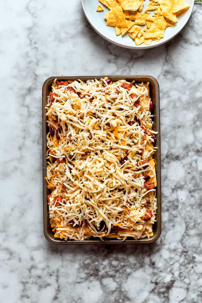 Shredded cheese is added as the final layer.