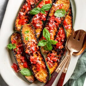 overhead photo of seared and roasted zucchini with fresh tomato sauce