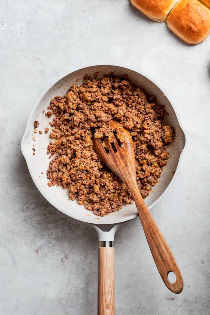 Condiments are mixed into a pan of ground beef.