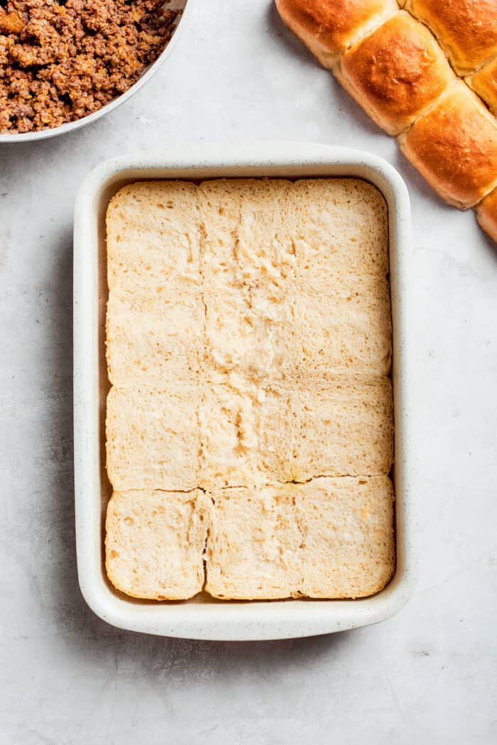The bottom half of rolls are added to a pan.