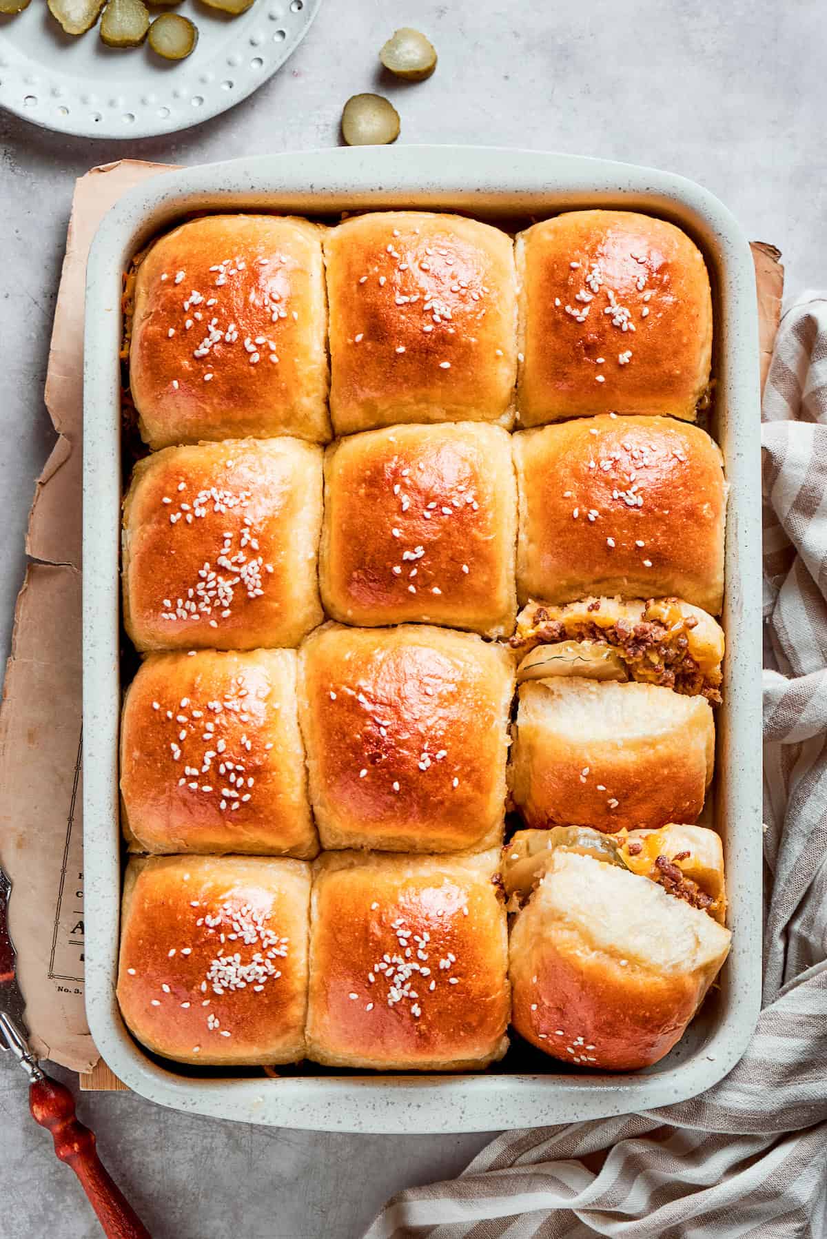 A pan of 12 baked cheeseburger sliders in a pan.