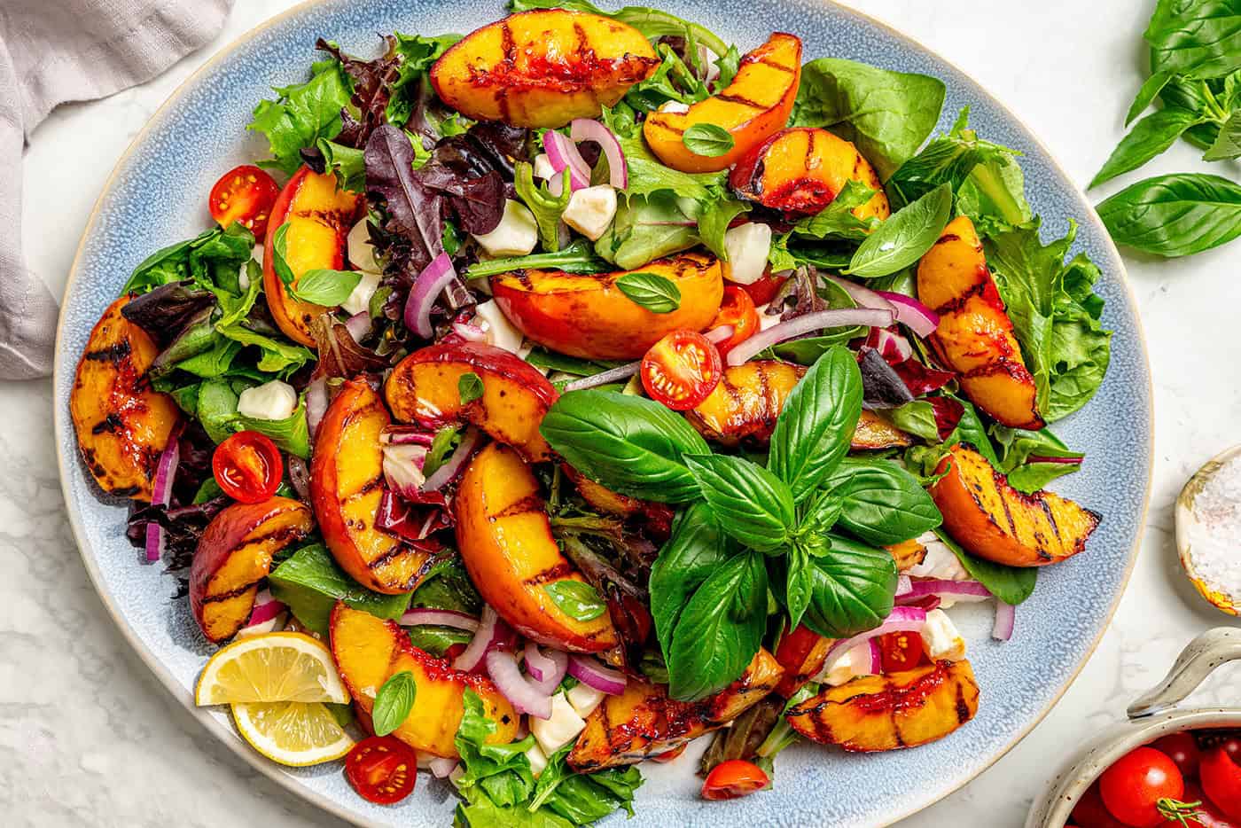 an oval platter of salad with grilled peaches