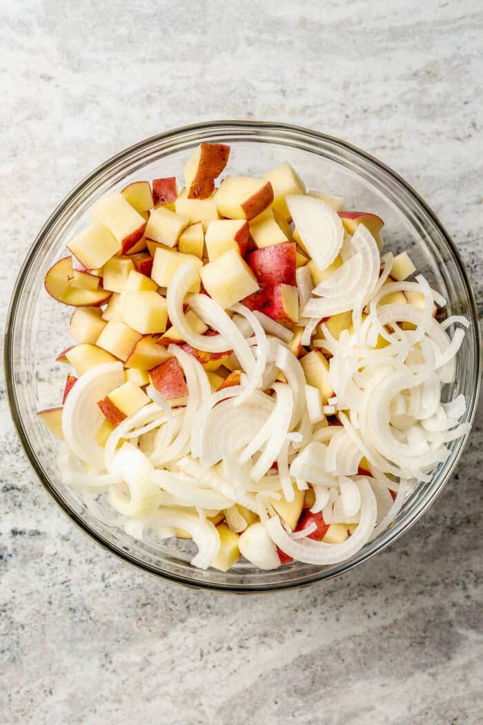 Potatoes and onions are combined in a bowl.