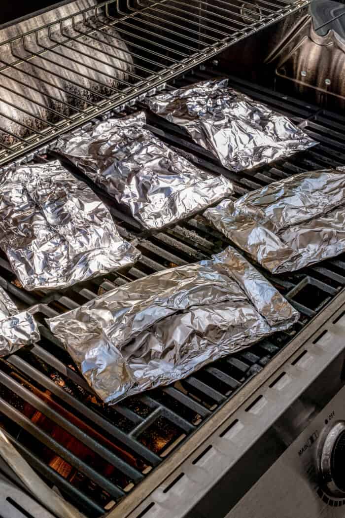 Grilled potato packets wrapped in foil on the grill.