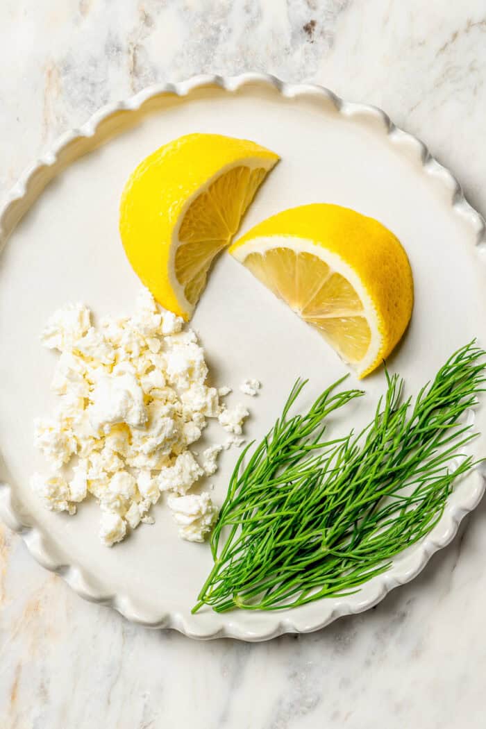 Lemon wedges, feta, and dill on a p late.