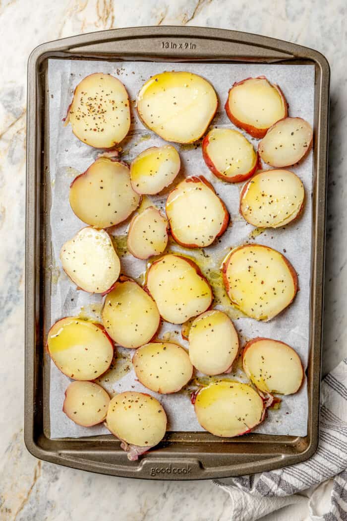 Slices of red potatoes on a baking tray.