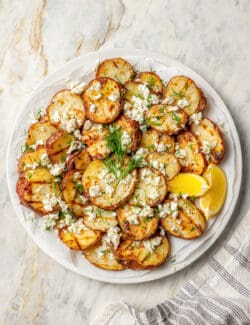 A plate of grilled red potatoes with lemon, feta, and dill.