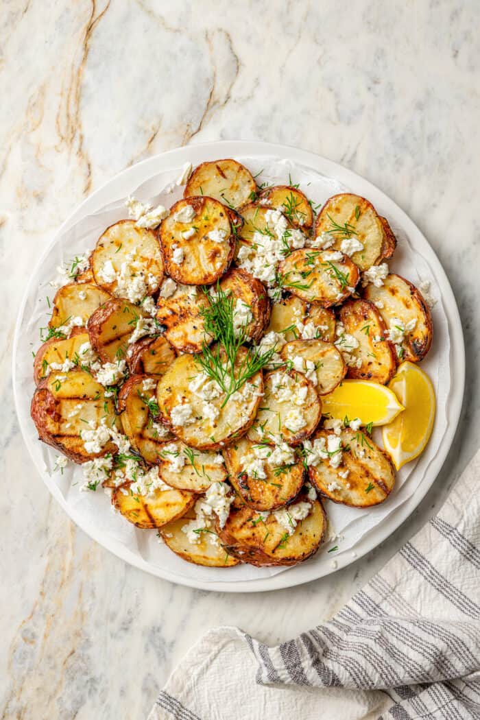 A plate of grilled red potatoes with lemon, feta, and dill.