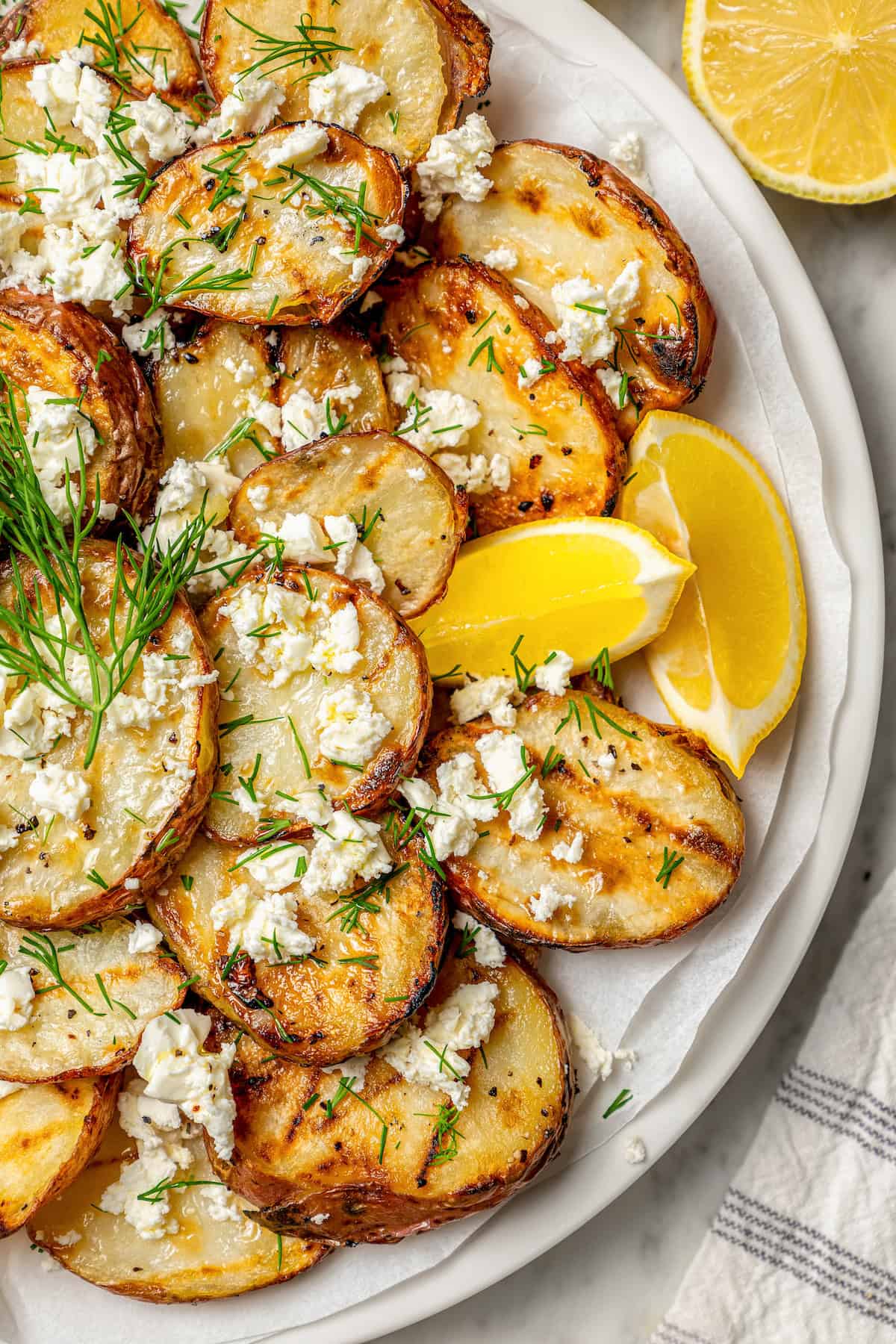 Lemon wedges are tucked in between sliced of grilled red potatoes.