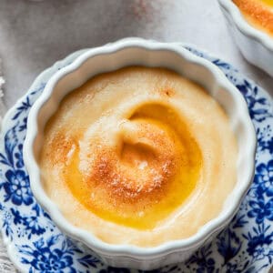 Rømmegrøt is served in a decorative bowl on top of a blue and white plate.