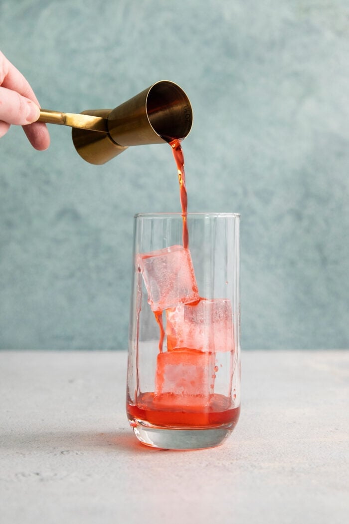 Campari is poured over a glass of ice.