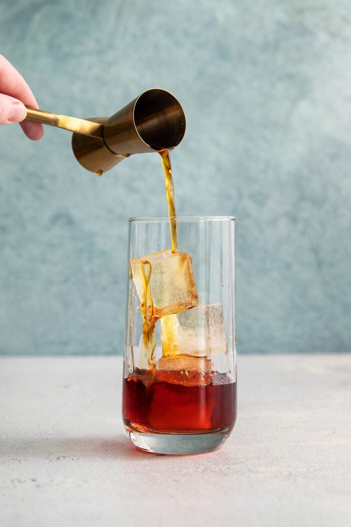 Sweet vermouth is added to a glass of Americano cocktail.