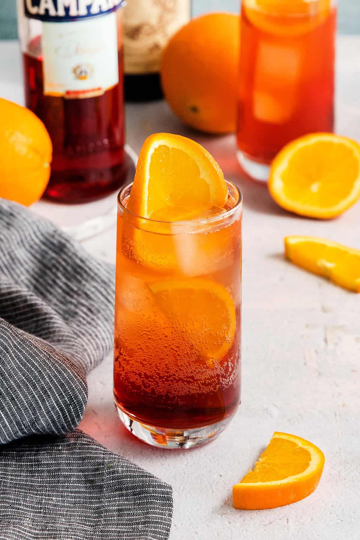 Orange slices garnish a tall bubbling glass of Americano cocktail.