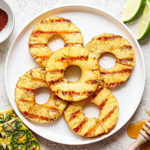 Five rings of grilled pineapple on a white plate.