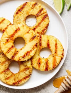 Grilled pineapple rings with char marks on a plate.