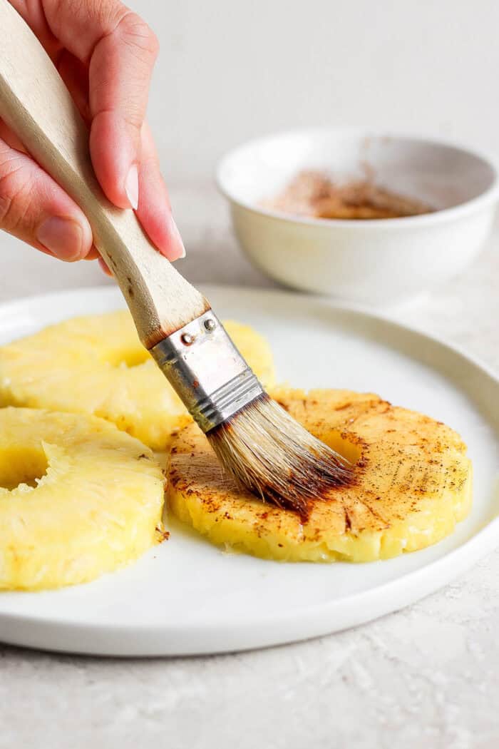 A pastry brush brushes pineapple with marinade.