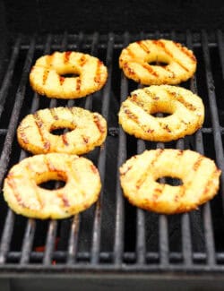 Char marks form on rings of pineapple as they grill.