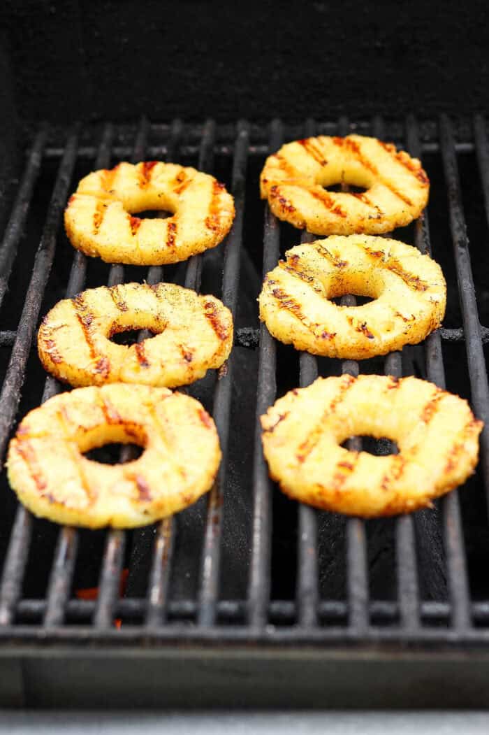 Char marks form on rings of pineapple as they grill.