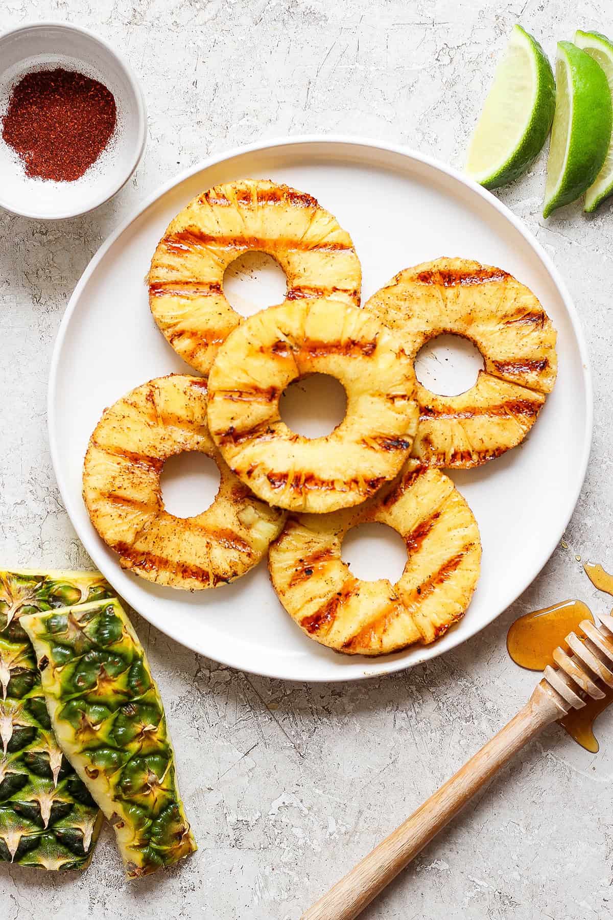 Five rings of grilled pineapple on a white plate.