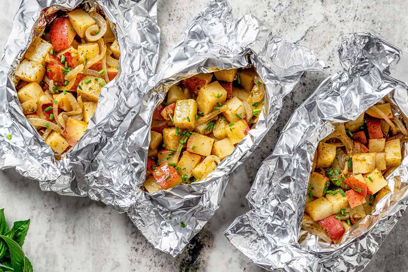 overhead photo of 3 foil packets of grilled potatoes