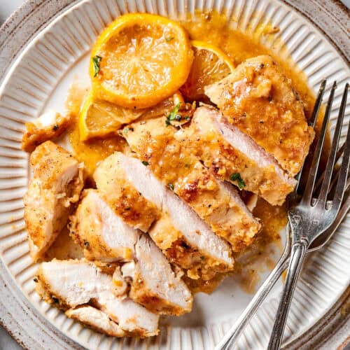 a sliced chicken breast with lemon and pepper, on a plate
