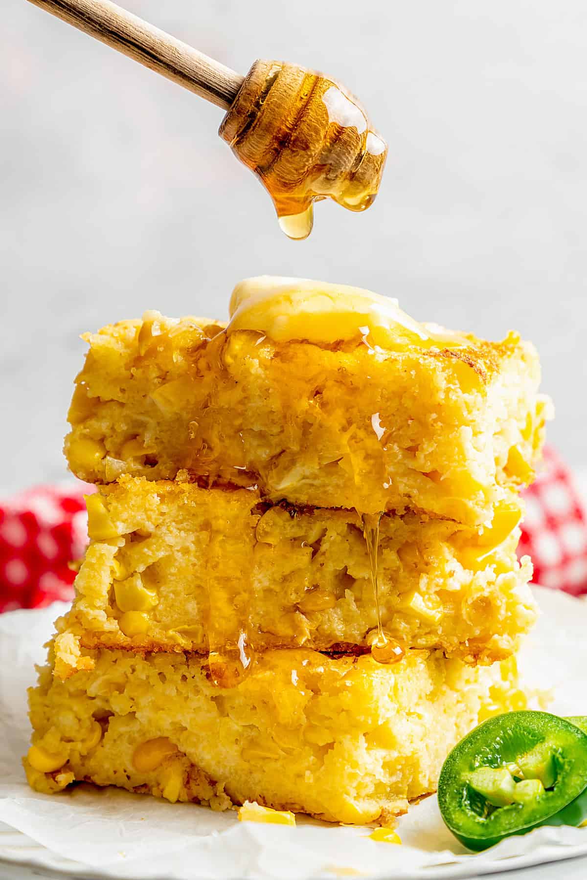 a stack of Jiffy corn casserole pieces, with honey being drizzled over the top