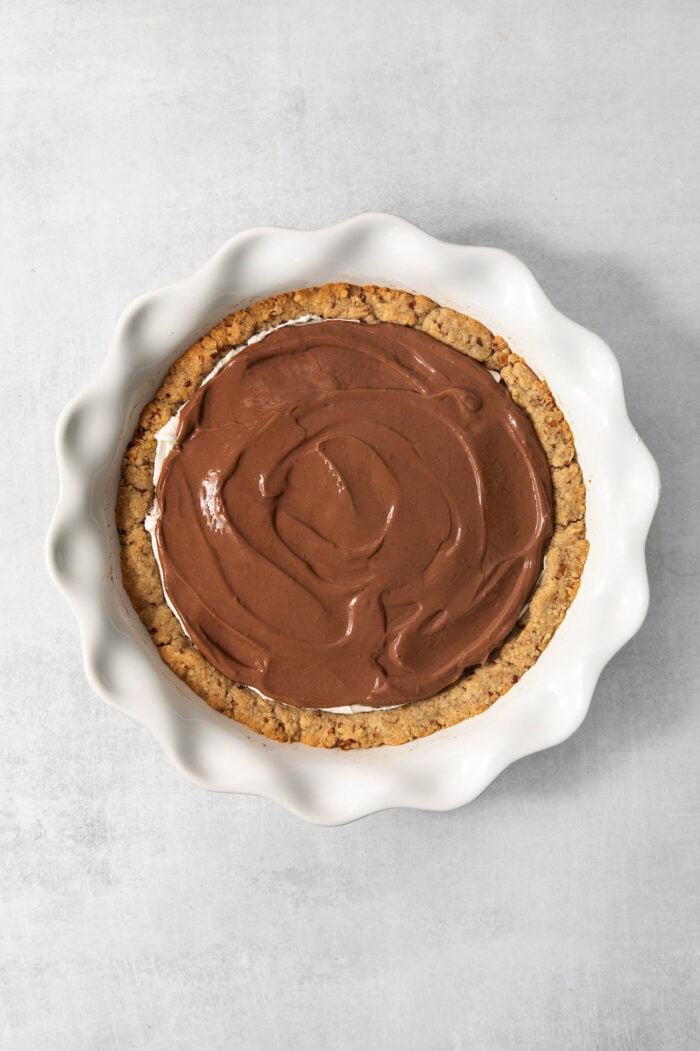 Spreading the chocolate pudding mixture over the cream cheese mixture.