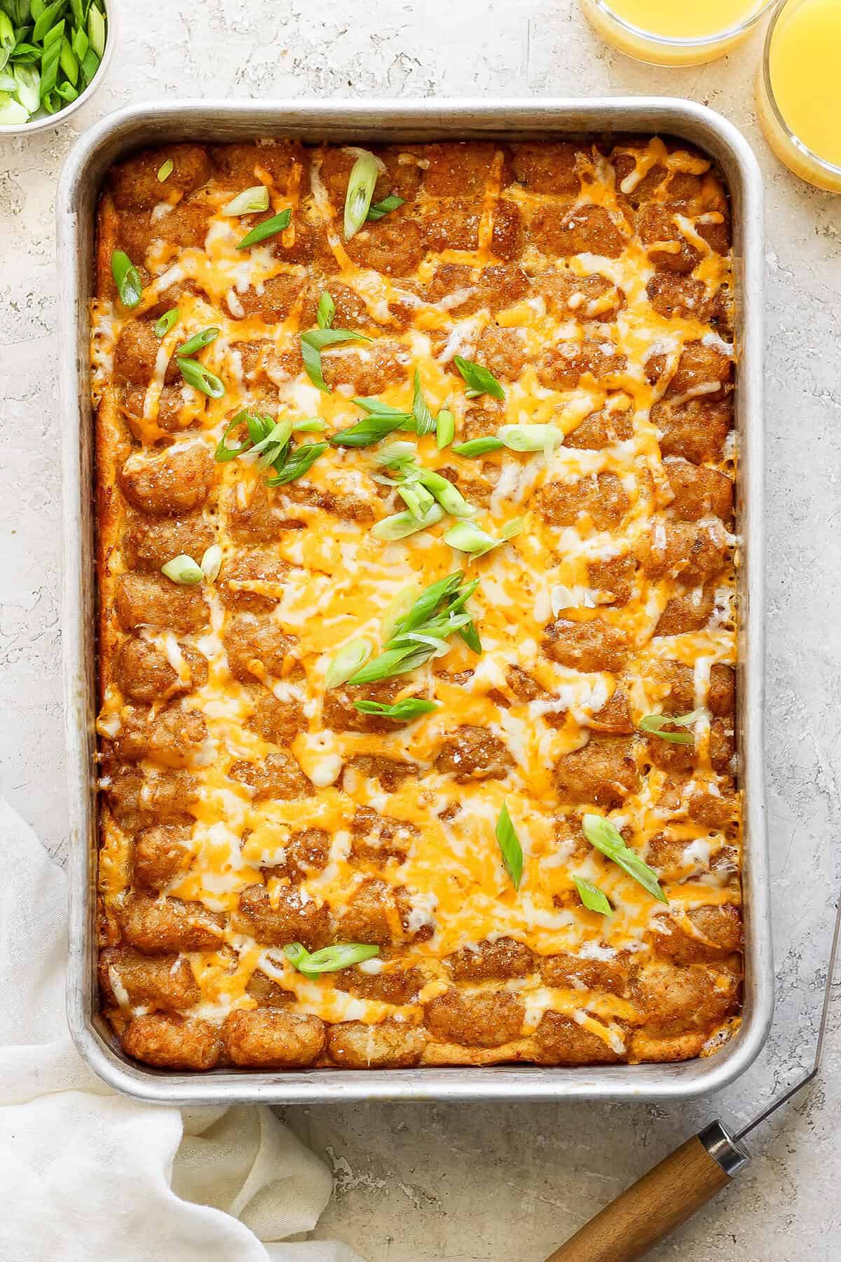 This garlicky tater tot breakfast casserole recipe with red peppers, onions, and sausage is an effortless morning bite. Baked tater tot casserole with melty cheese on top.