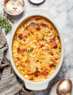 overhead photo of a serving spoon in a baking dish of cheesy scalloped potatoes