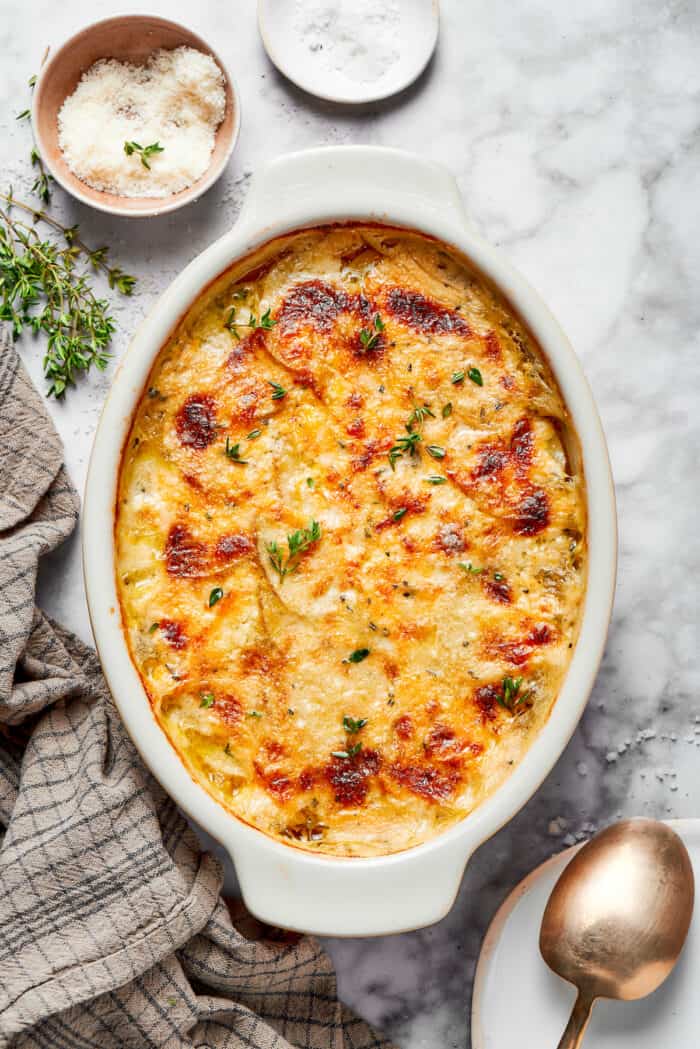 overhead photo of a serving spoon in a baking dish of cheesy scalloped potatoes