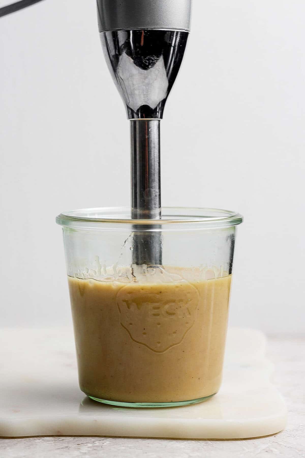 Processing the dressing with an immersion blender. 